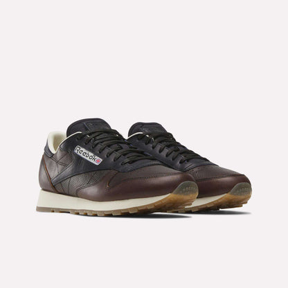 Reebok x C.F. Stead Classic Leather Shoes by Reebok in dark brown and black feature beige soles, white lining, the Reebok logo, and premium full-grain leather uppers, shown against a plain light background.