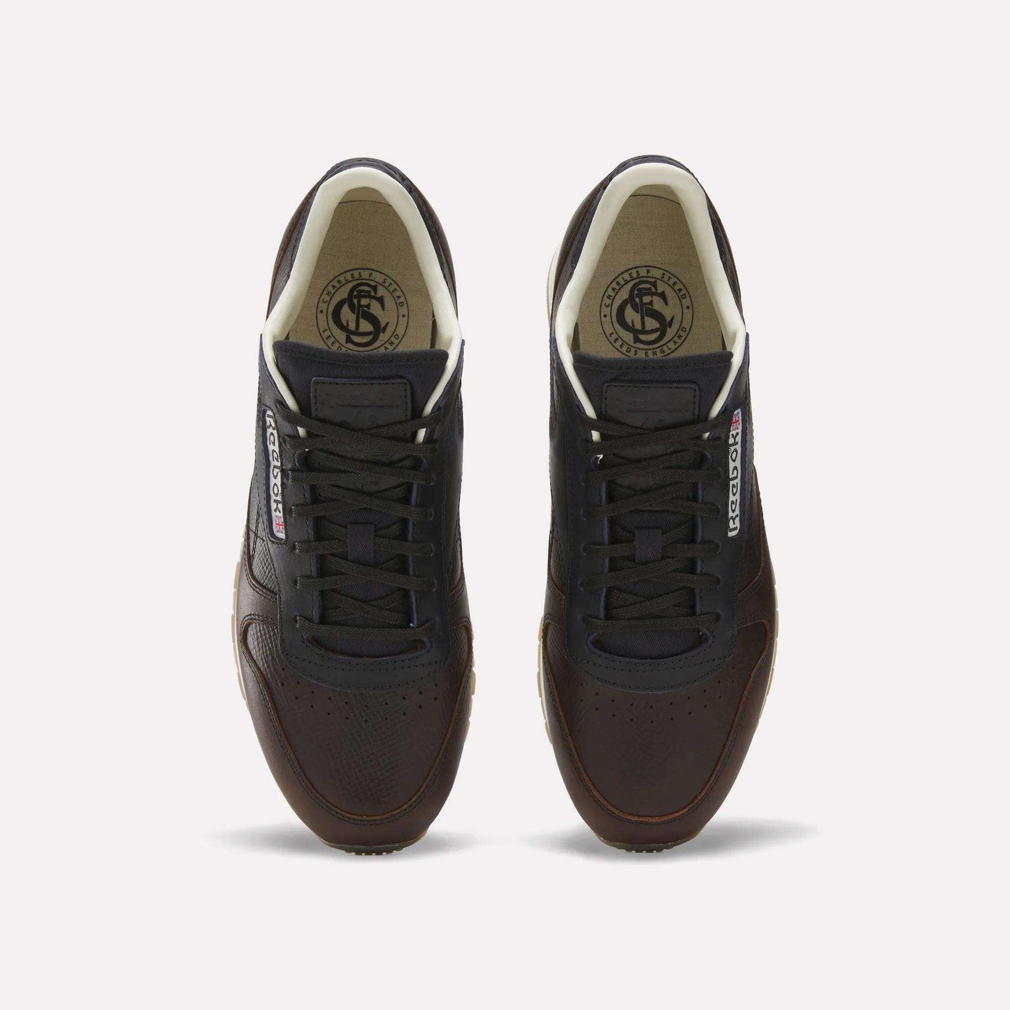The Reebok x C.F. Stead Classic Leather Shoes feature dark brown luxe leather, black laces, white inner lining, and Reebok logos on the tongue and side, shown from above against a plain white background.