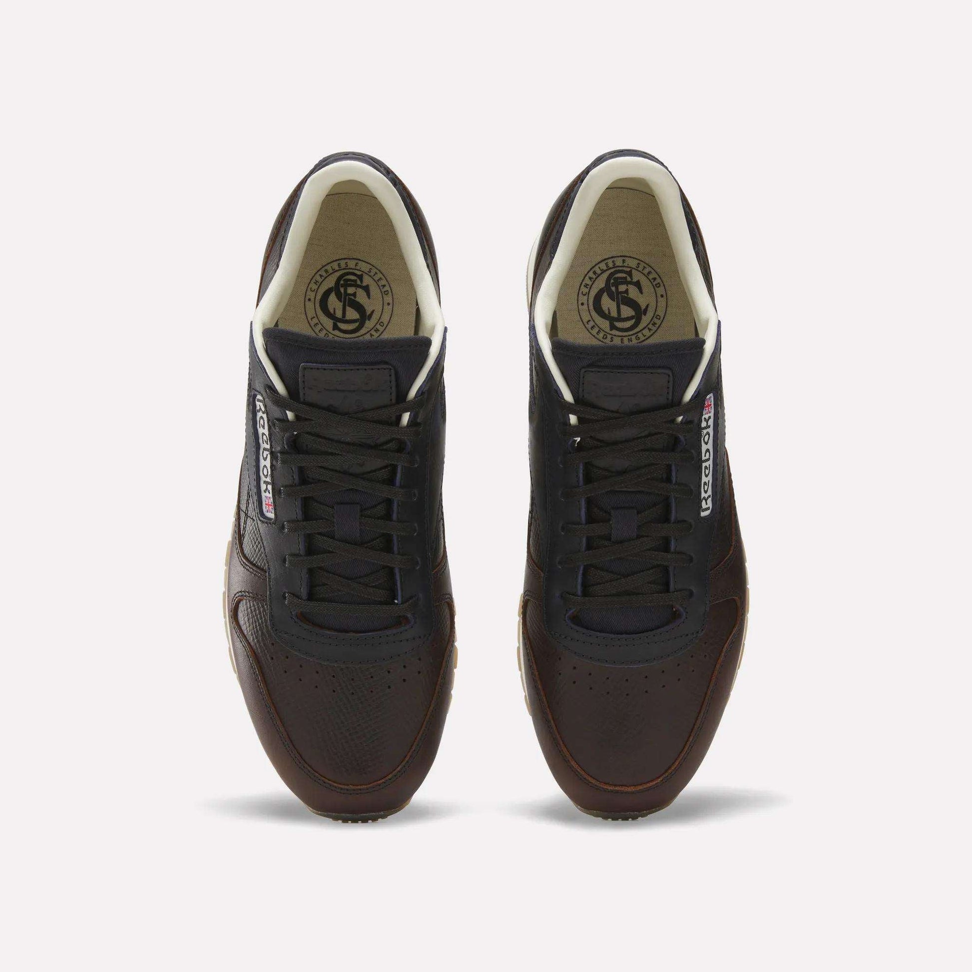 The Reebok x C.F. Stead Classic Leather Shoes feature dark brown luxe leather, black laces, white inner lining, and Reebok logos on the tongue and side, shown from above against a plain white background.