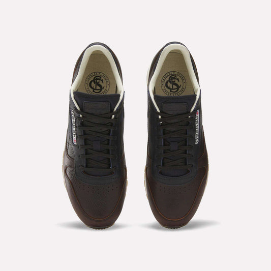 The Reebok x C.F. Stead Classic Leather Shoes feature dark brown luxe leather, black laces, white inner lining, and Reebok logos on the tongue and side, shown from above against a plain white background.
