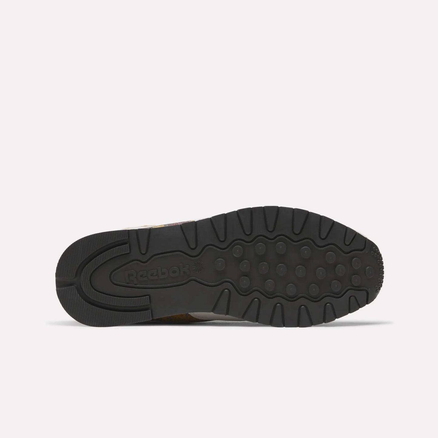 The image shows the black rubber outsole of the Reebok Classic Leather 1983 Vintage Shoes, featuring grooves, circular grips, and an embossed Reebok logo on the heel. The shoe lies flat with its sole facing up.