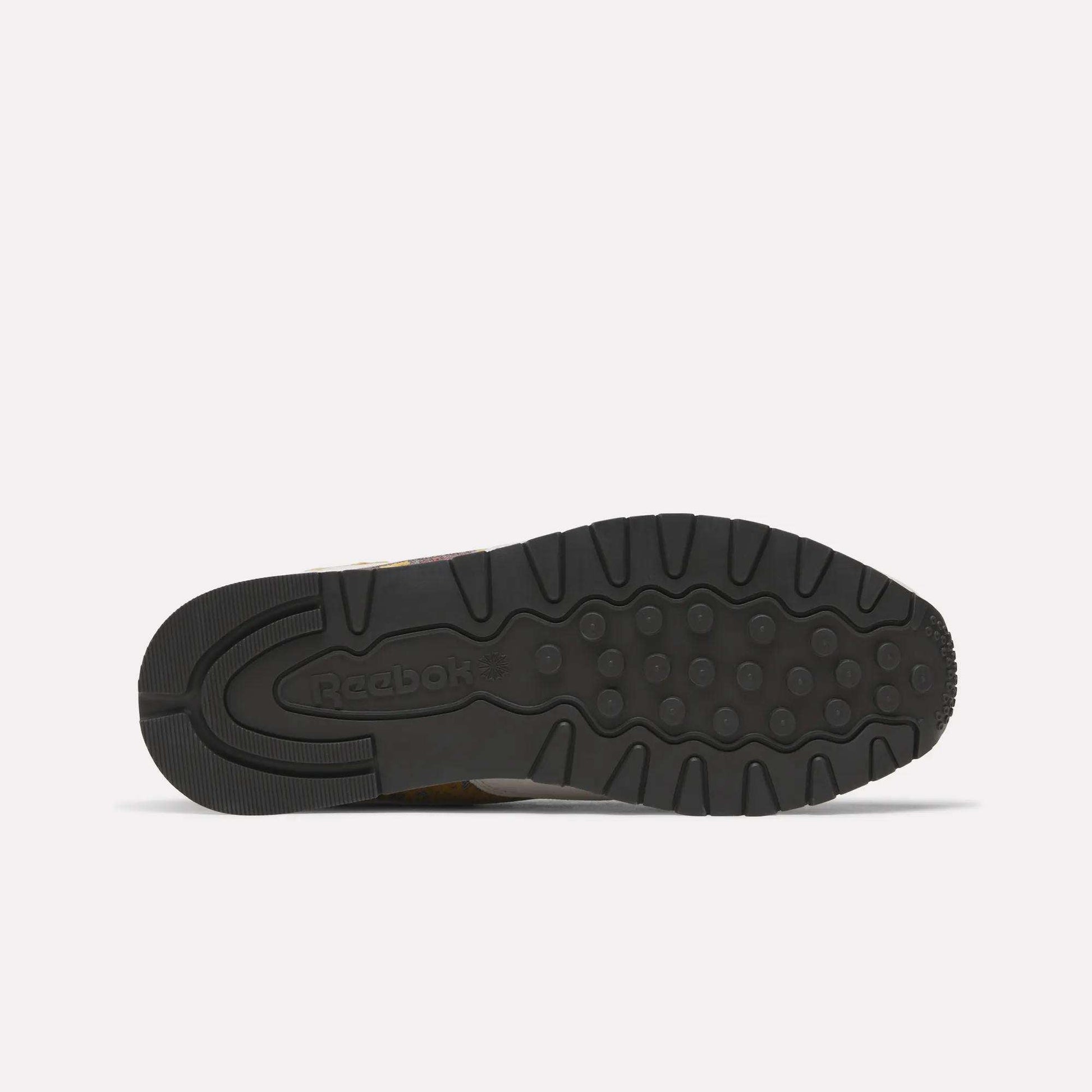 The image shows the black rubber outsole of the Reebok Classic Leather 1983 Vintage Shoes, featuring grooves, circular grips, and an embossed Reebok logo on the heel. The shoe lies flat with its sole facing up.