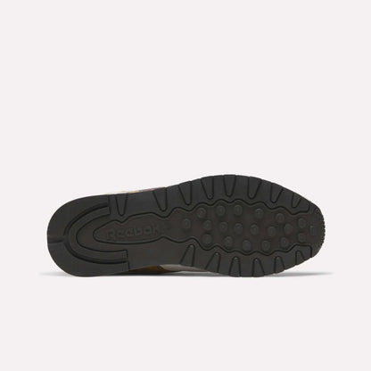 The image shows the black rubber outsole of the Reebok Classic Leather 1983 Vintage Shoes, featuring grooves, circular grips, and an embossed Reebok logo on the heel. The shoe lies flat with its sole facing up.