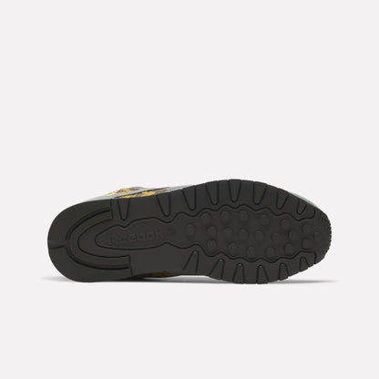 The image displays the underside of Reebok’s Classic Leather 1983 Vintage Shoes, featuring a black rubber sole with textured grip patterns and an embossed Reebok logo near the heel against a plain, light-colored background.