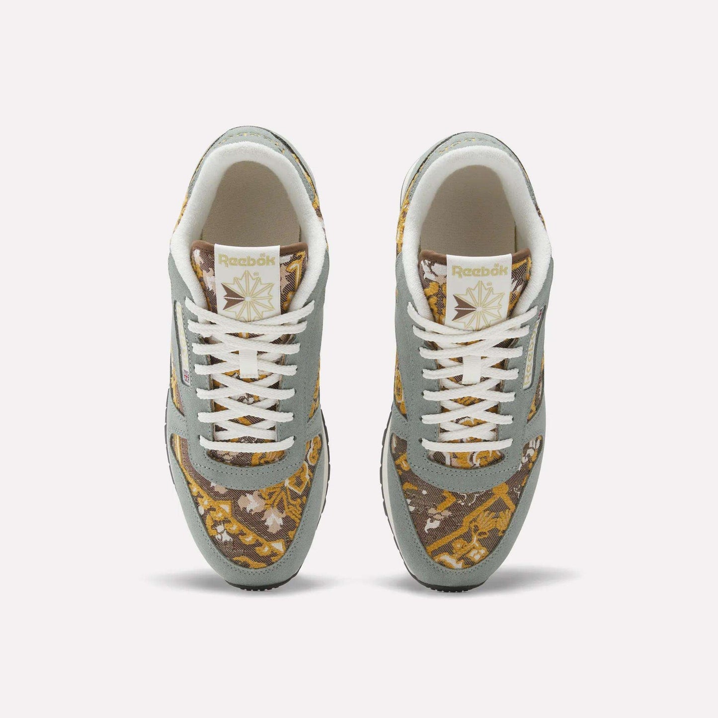 Top view of Reebok Classic Leather 1983 Vintage Shoes with light gray overlays, white laces, and a gold and brown patterned fabric on the toe box and sides, plus the Reebok logo on the tongue.