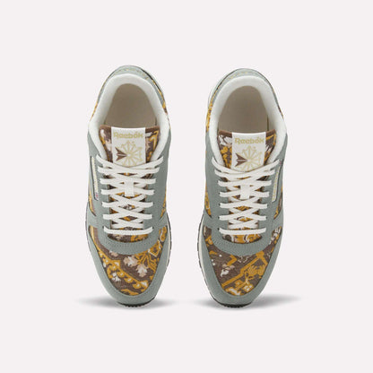 Top view of Reebok Classic Leather 1983 Vintage Shoes with light gray overlays, white laces, and a gold and brown patterned fabric on the toe box and sides, plus the Reebok logo on the tongue.