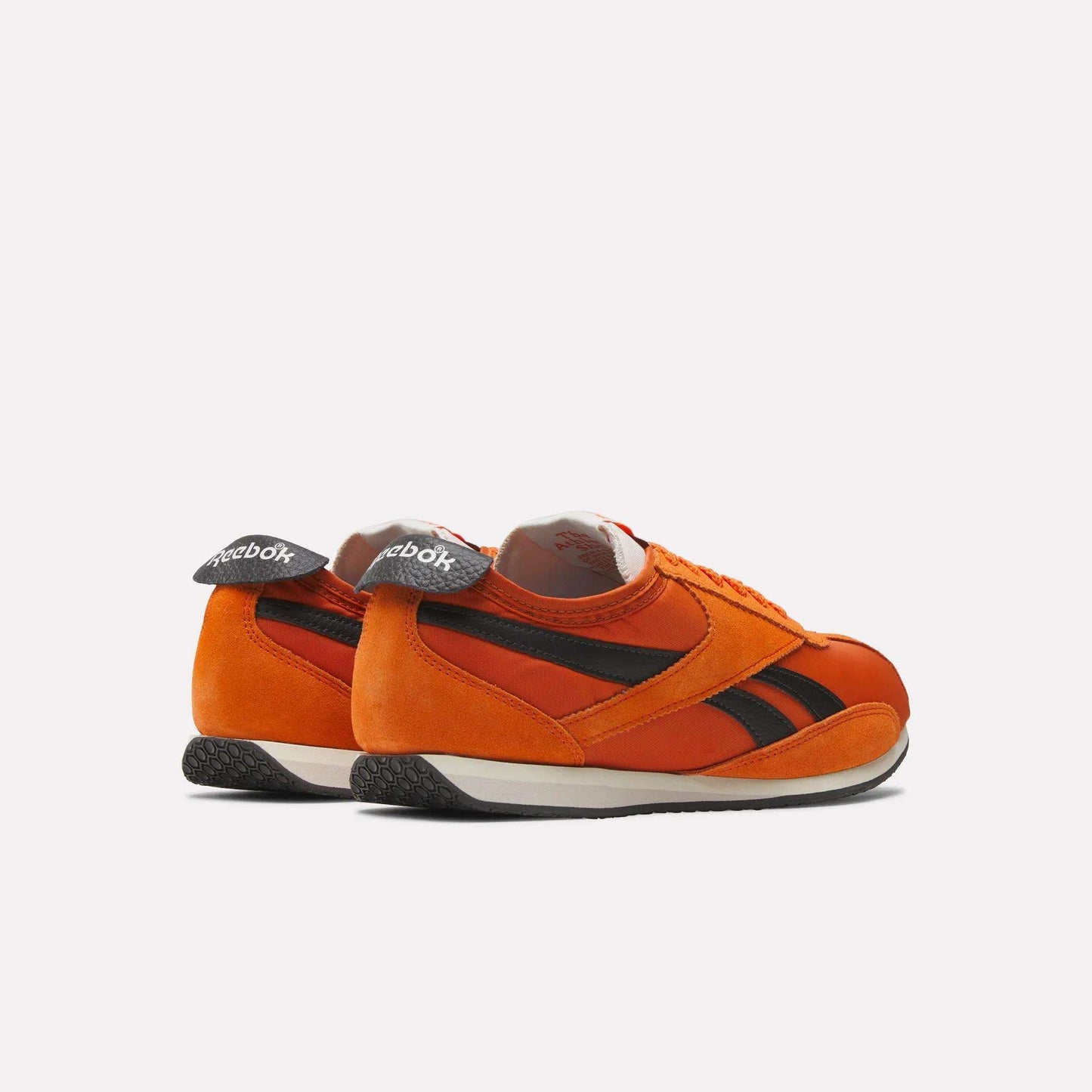 The Reebok R400 Shoes are retro track sneakers in orange with black stripes, white midsoles, and black textured outsoles, shown from the back and side against a plain light background.
