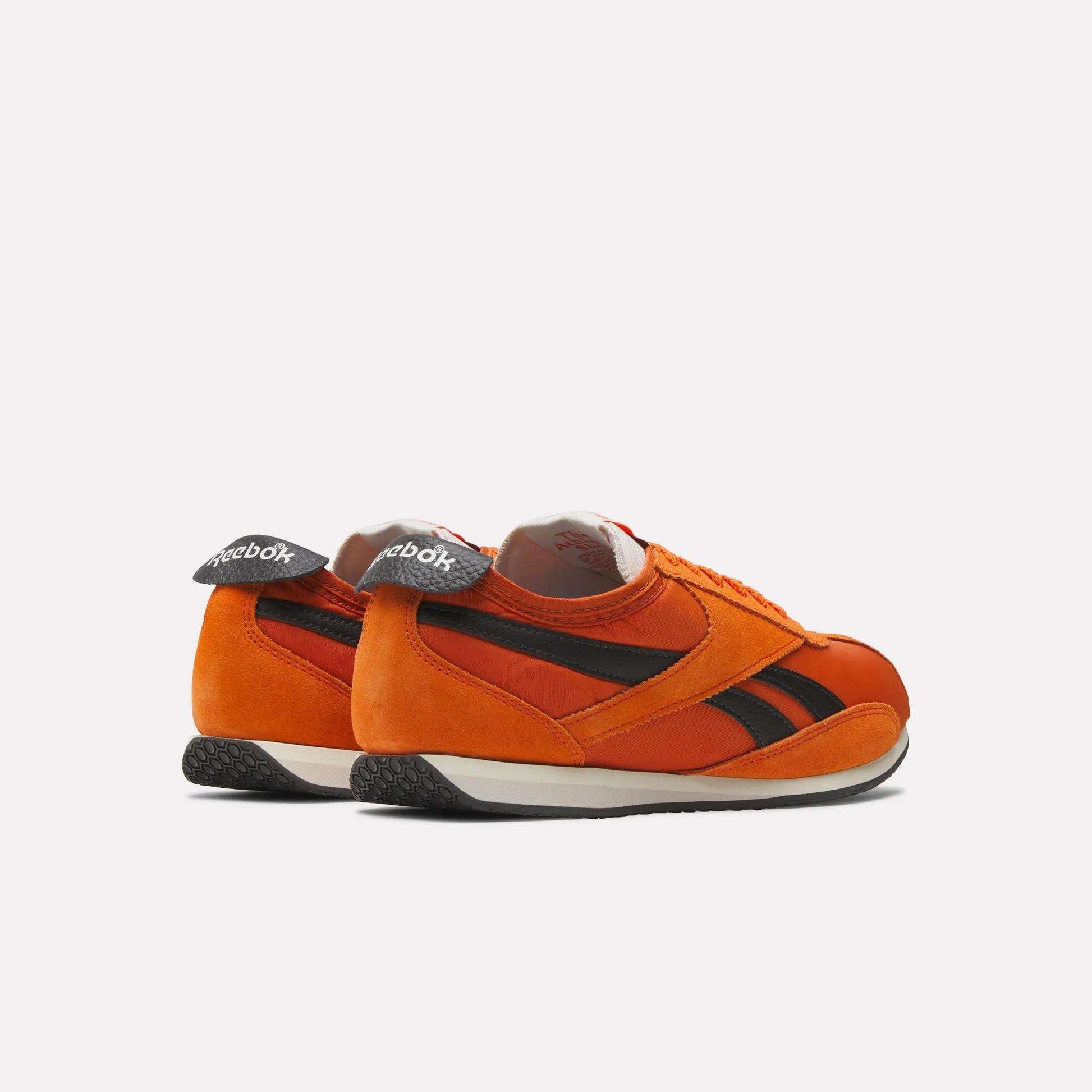 The Reebok R400 Shoes are retro track sneakers in orange with black stripes, white midsoles, and black textured outsoles, shown from the back and side against a plain light background.