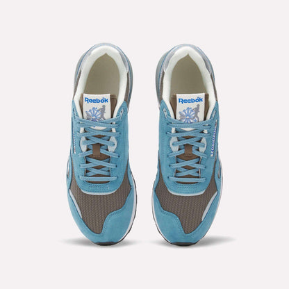 Top view of Reebok Classic Nylon 89 Shoes featuring blue suede overlays, brown mesh panels, grey accents, and a cushioned midsole. White tongue labels display the Reebok logo and vector. Stylish vintage running sneakers.