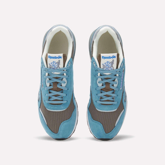 Top view of Reebok Classic Nylon 89 Shoes featuring blue suede overlays, brown mesh panels, grey accents, and a cushioned midsole. White tongue labels display the Reebok logo and vector. Stylish vintage running sneakers.