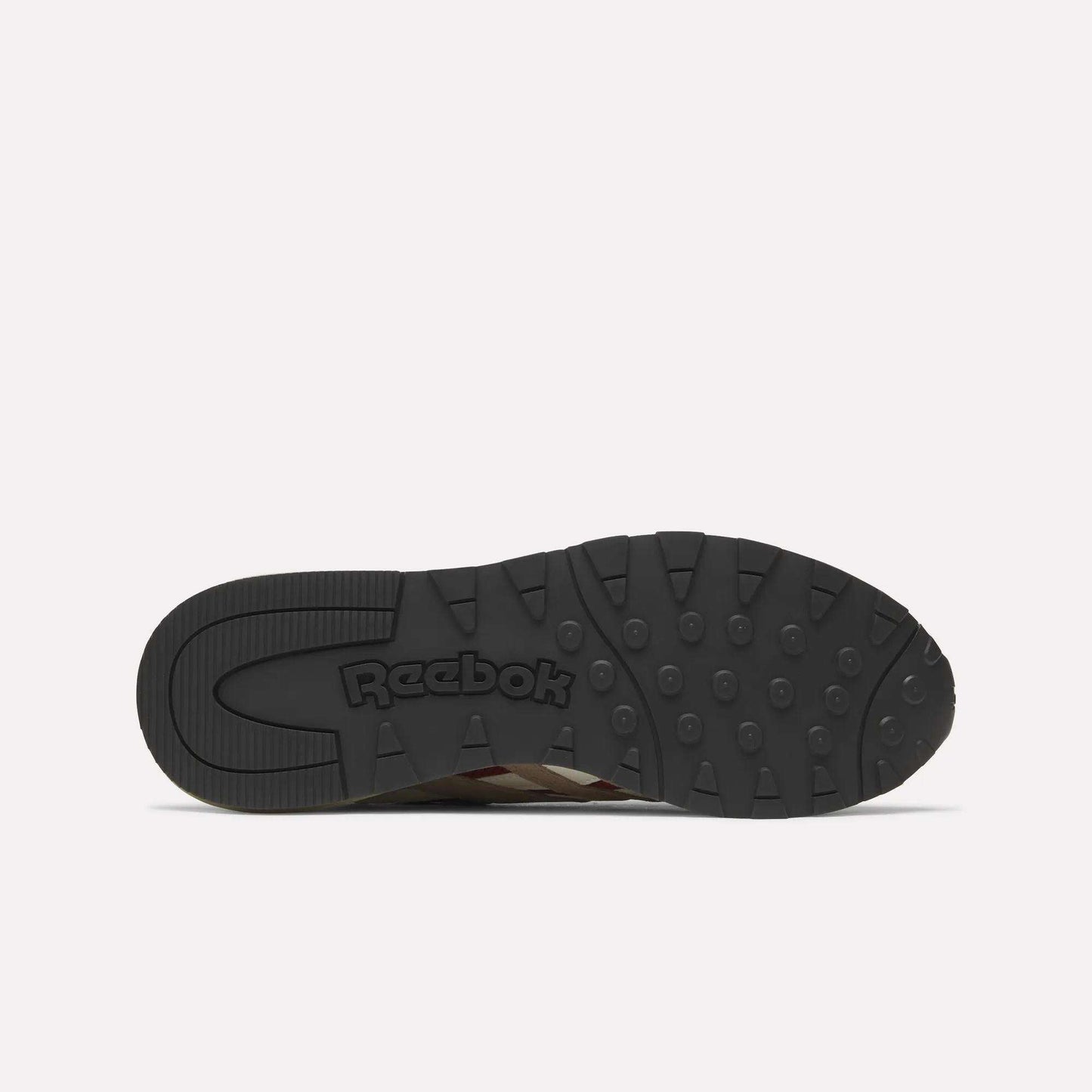The image displays the black rubber outsole of a Reebok Classic Nylon 89 Shoe, viewed from below. It features circular grips, embossed Reebok branding near the heel, and suggests a cushioned midsole typical of classic running shoes.
