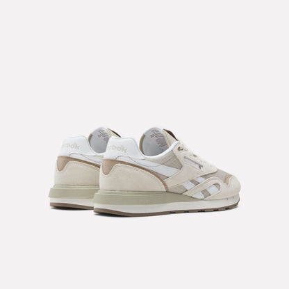 A pair of Reebok Classic Nylon 89 Shoes in beige and white, with suede and mesh panels, cushioned midsole, Reebok logo, and retro design, shown from the back and side on a white background.