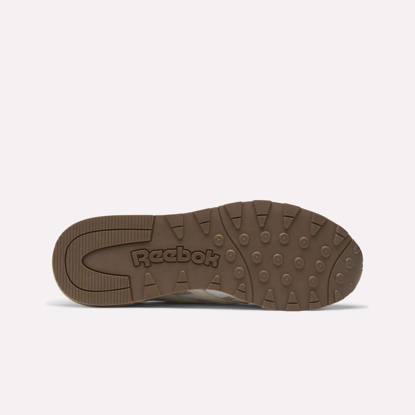 The image shows the bottom view of Reebok Classic Nylon 89 Shoes with a brown rubber sole featuring circular treads and the Reebok logo embossed in the center. The plain white background highlights this vintage design.