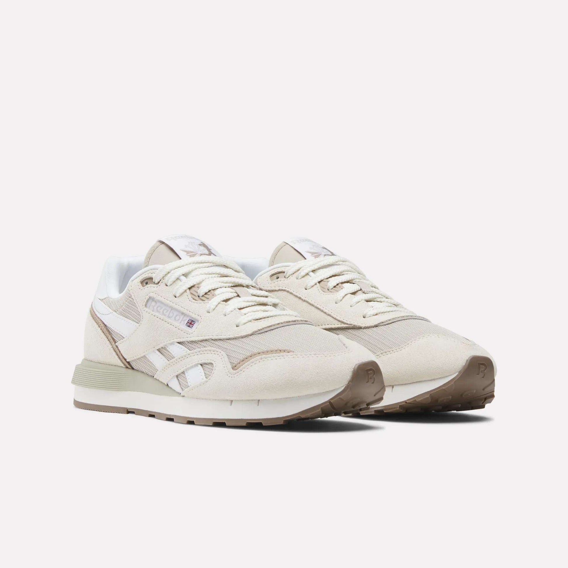 A pair of Reebok Classic Nylon 89 Shoes in beige with white accents, featuring suede and mesh details, a cushioned midsole, and a gum rubber sole, are positioned side by side on a plain white background.