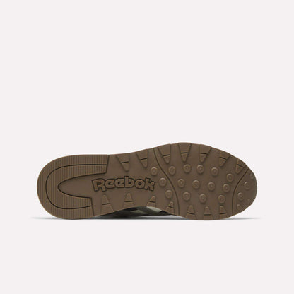 The image shows the bottom view of a brown Classic Nylon 89 Shoes sole by Reebok, featuring circular and rectangular grip patterns with the Reebok logo embossed in the center.