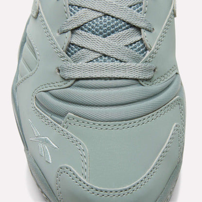 Close-up view of the toe and laces of the Brutus Low Shoes by Reebok, showcasing detailed stitching, logo embroidery, a mesh tongue, smooth synthetic overlays, and an EVA midsole for lightweight comfort.