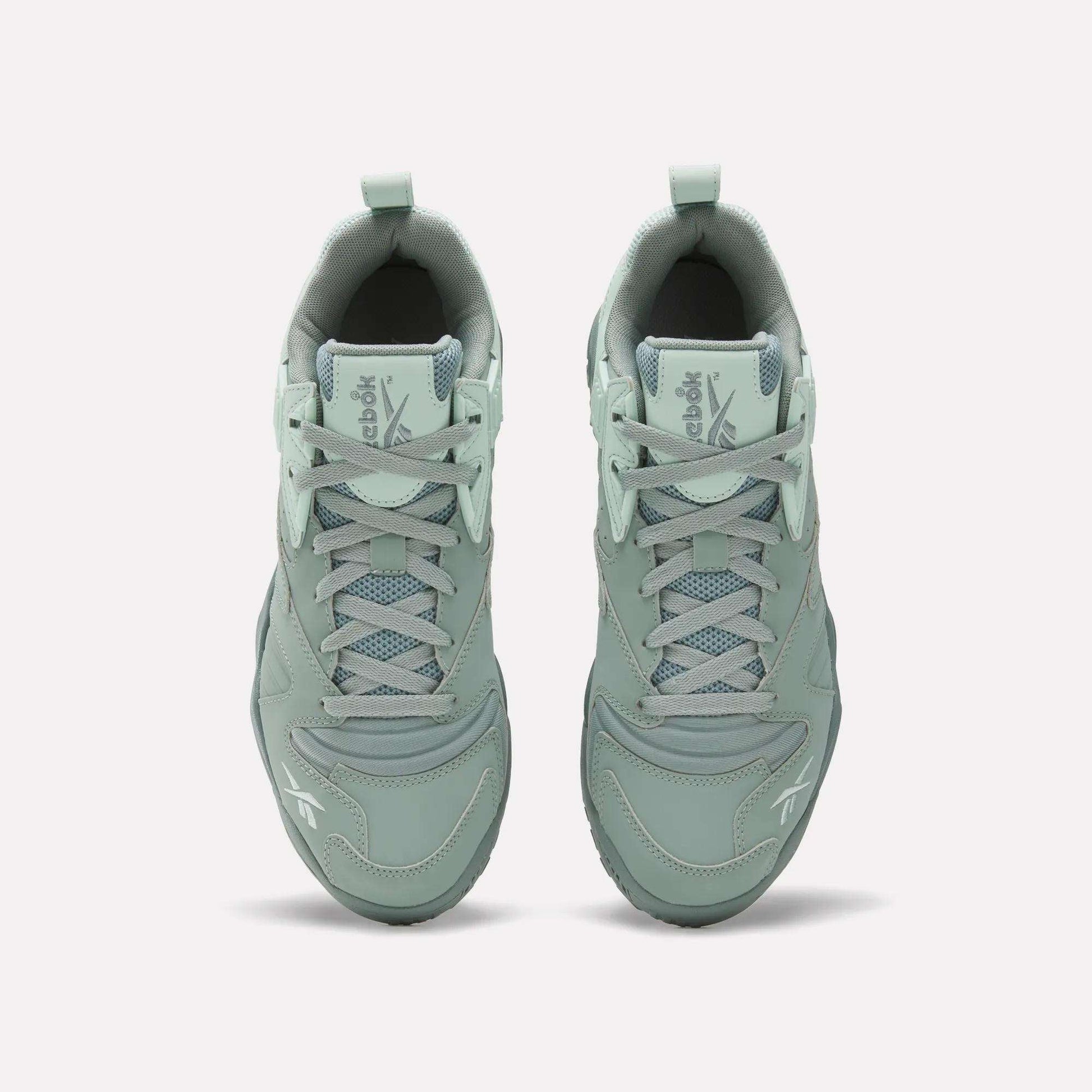 Top view of Reebok Brutus Low Shoes in light green with laces, mesh detailing, and Reebok logos on the tongue and toe. Features an EVA midsole for comfort, shown on a plain white background.