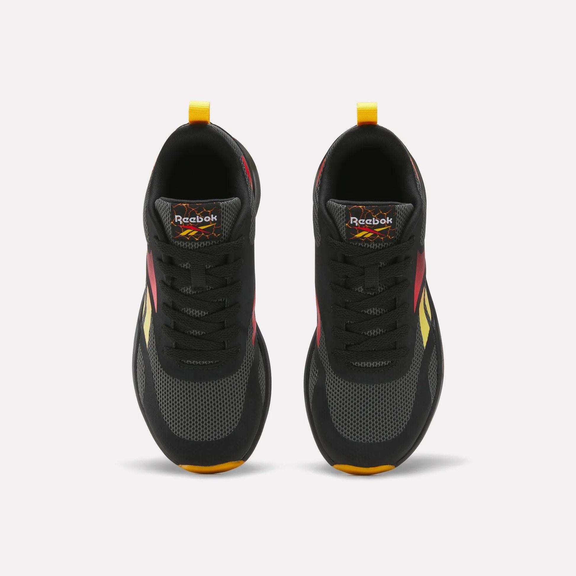 Top view of a pair of Reebok Energen Running Shoes for little kids in black with red, yellow, and orange accents, black laces, and yellow heel pull tabs. These shoes feature a cushioned midsole for added comfort and are positioned side by side on a white background.