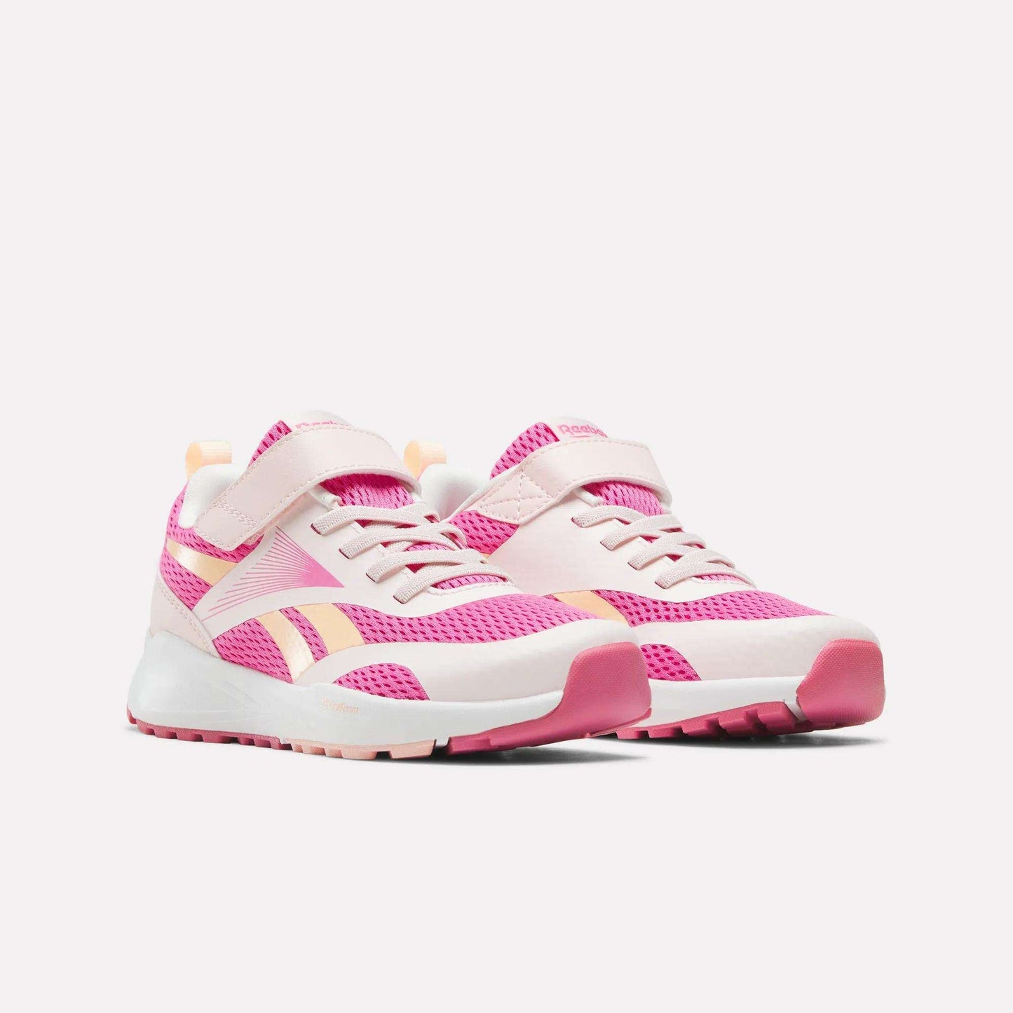 A pair of Reebok Energen Running Shoes for little kids, featuring pink and white mesh uppers, Velcro straps, laces, pink outsoles, and peach accents—all showcased against a plain white background.