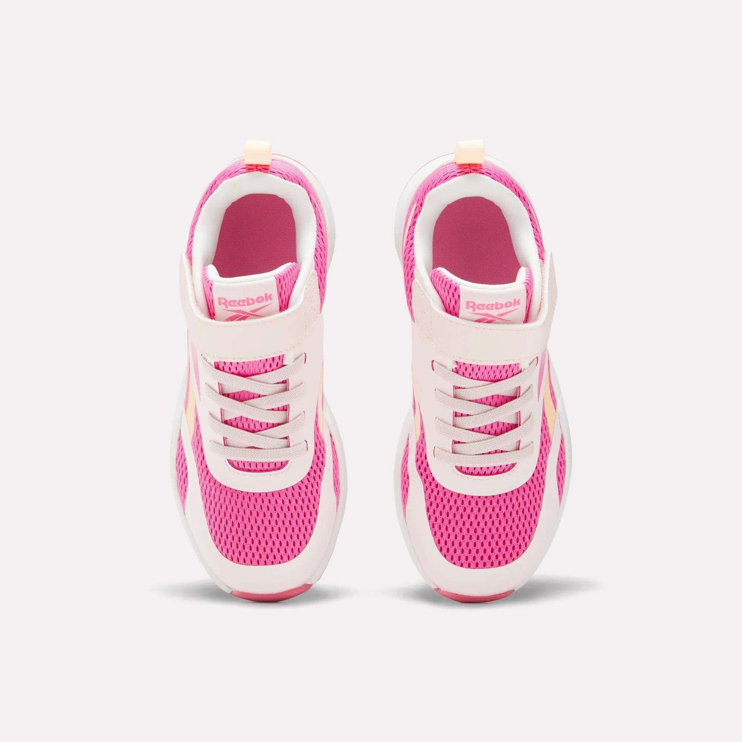 A pair of Reebok Energen Running Shoes for little kids in pink and white, viewed from above, showcasing breathable mesh uppers, laces, and a Velcro strap on each shoe, set against a light background.