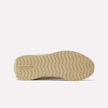 A beige, zigzag-patterned rubber outsole of the Reebok Women’s Classic AZ Shoes is shown from the bottom, featuring an embossed logo near the heel against a plain white background that highlights these sleek runners.