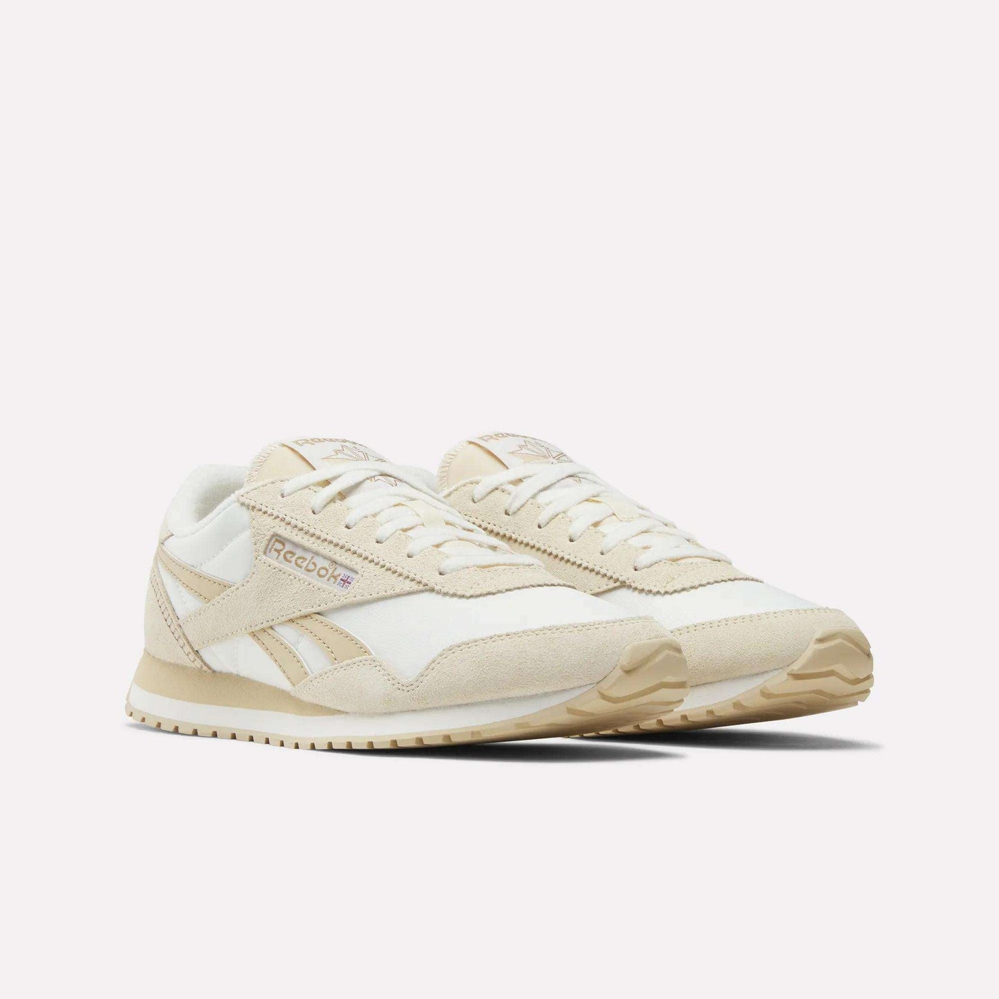 Reebok Women's Classic AZ Shoes in beige and white are shown on a plain white background, featuring a retro low-profile design with suede and mesh panels, beige soles, and Reebok branding on the side.