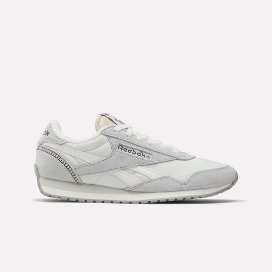 The Reebok Women's Classic AZ Shoes are white sneakers with grey accents, light grey suede details, and the Reebok logo on the side. These lace-up runners offer a low-profile silhouette and flat rubber sole for everyday comfort.