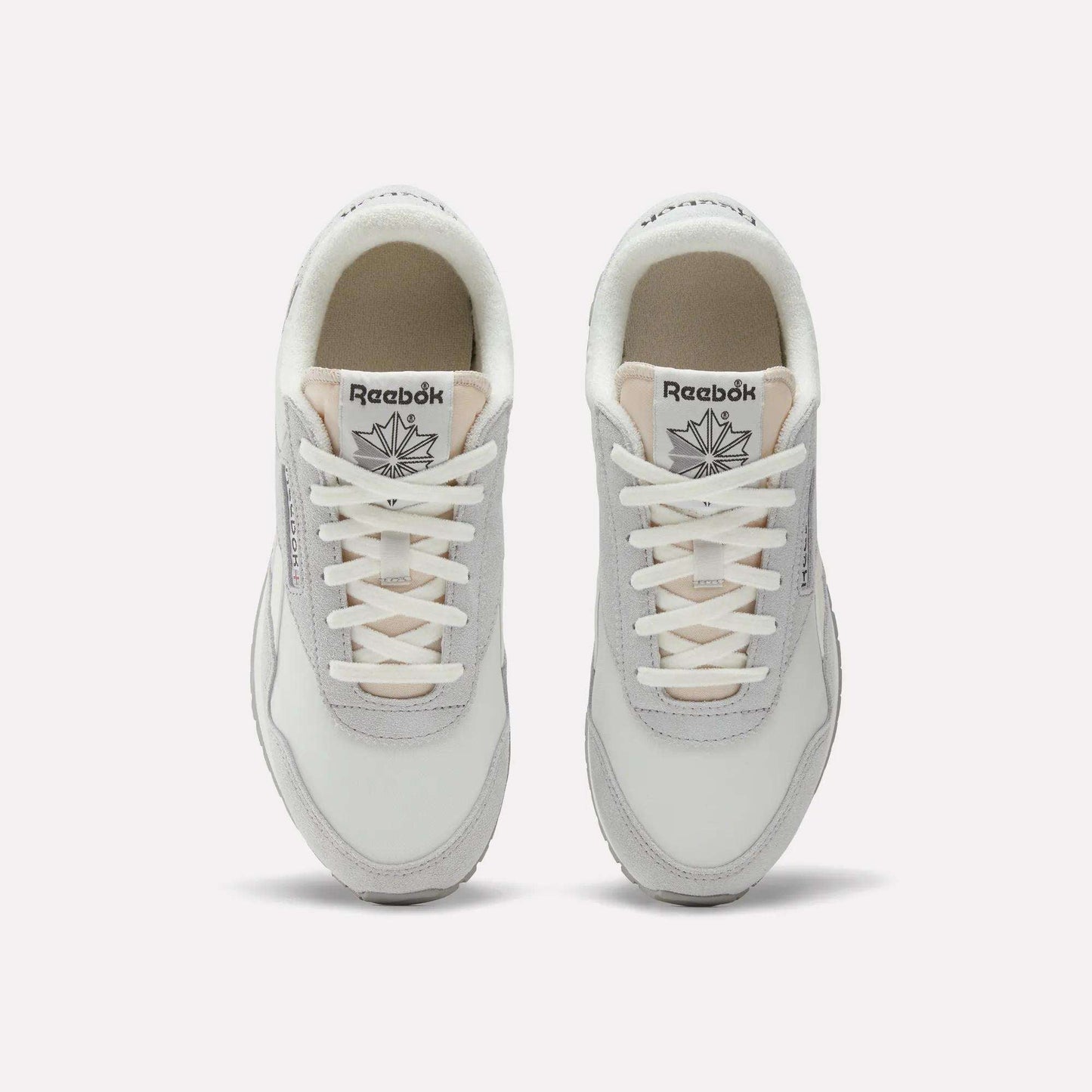 Top view of a pair of Women's Classic AZ Shoes by Reebok in white and light gray with white laces, low-profile design, and the Reebok logo visible on each tongue, displayed side by side on a plain background.