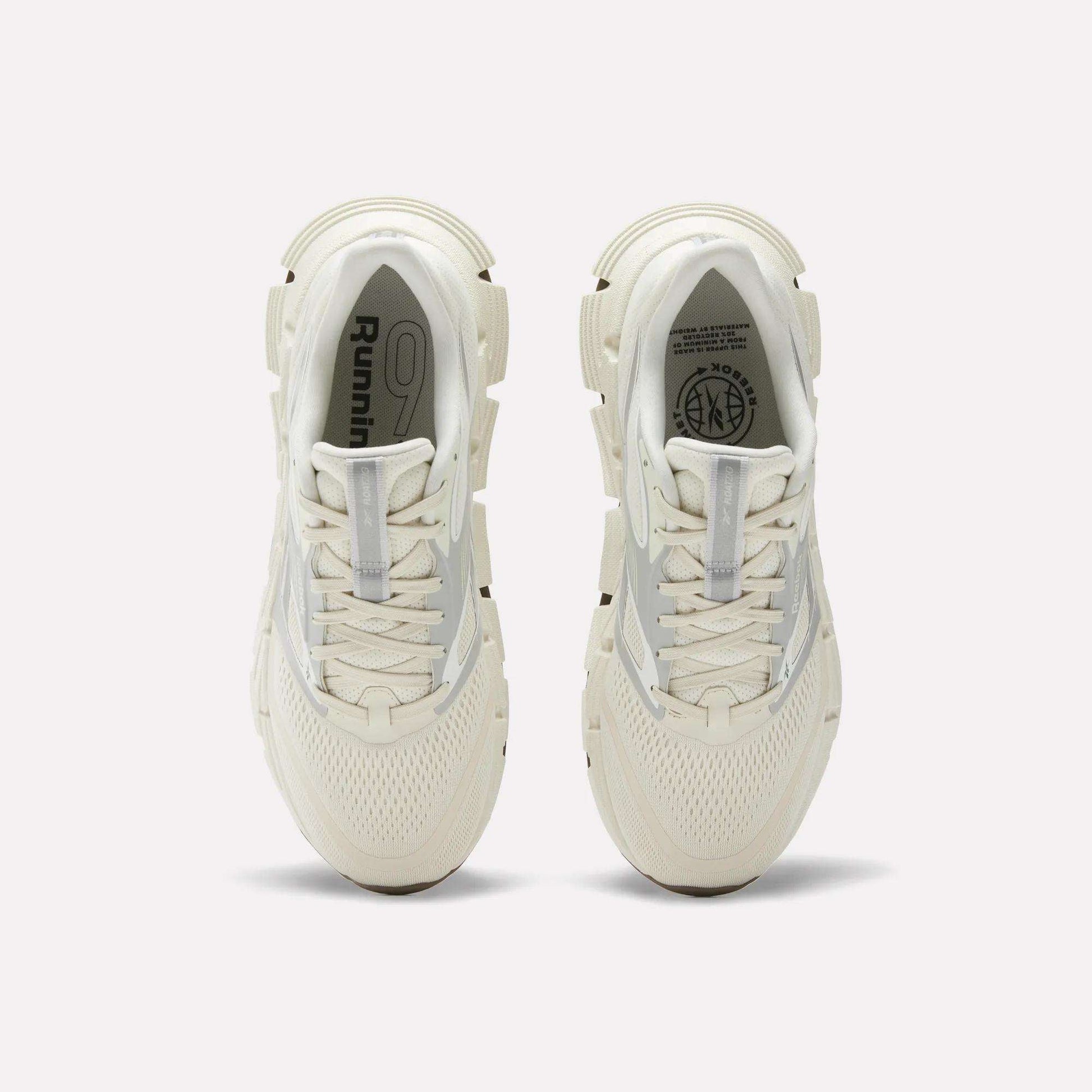 A pair of white Reebok Men's FloatZig 2 Running Shoes viewed from above, featuring mesh uppers, laces, cushioned Superfloat+ soles, and Running logo details on the insoles.