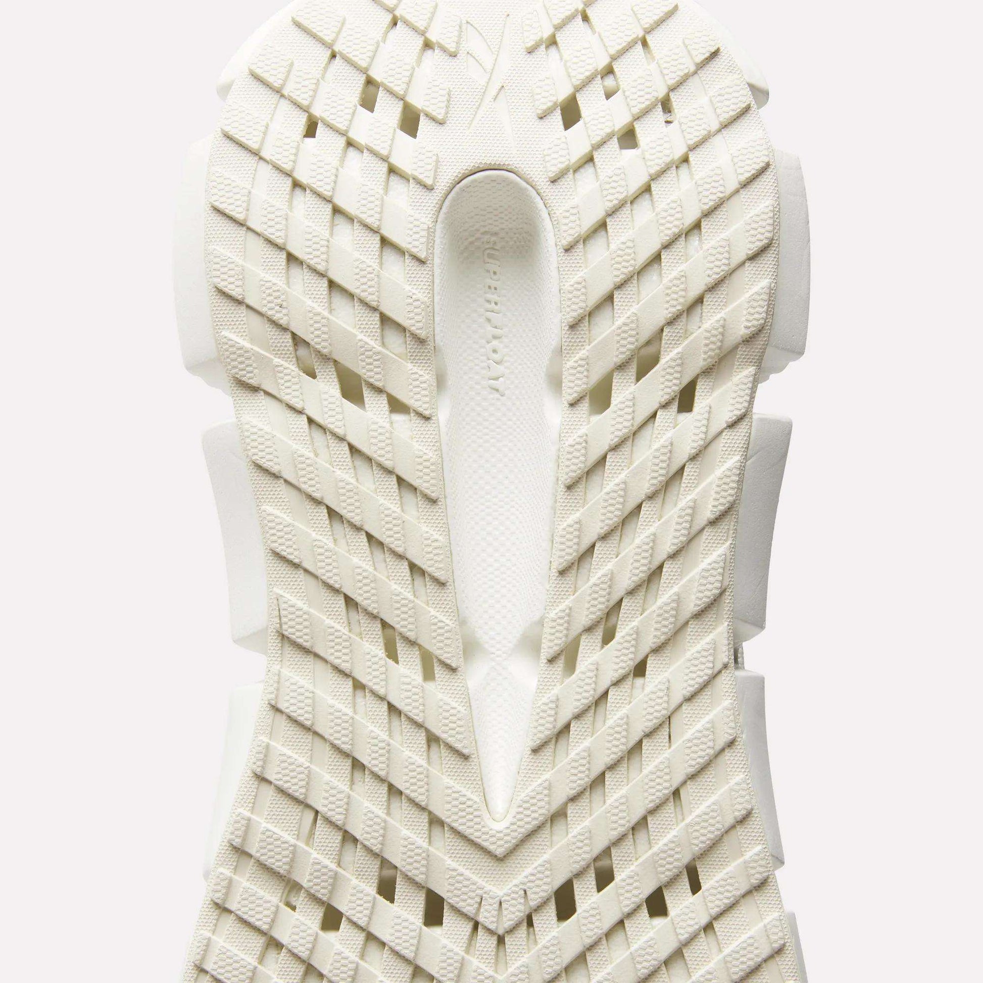 Close-up of the sole of Reebok Women's FloatZig 2 Running Shoes, featuring a white geometric grid tread and textured surface viewed from below, with subtle branding in the center to highlight its energy-returning cushioning.