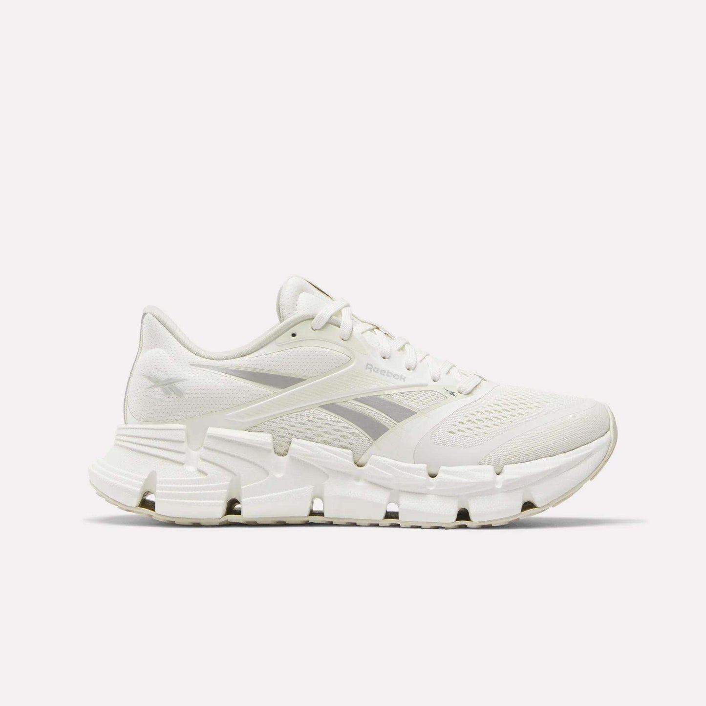 Side view of a white Reebok Women's FloatZig 2 Running Shoe featuring a mesh upper, unique angular outsole, and energy-return cushioning for comfort.
