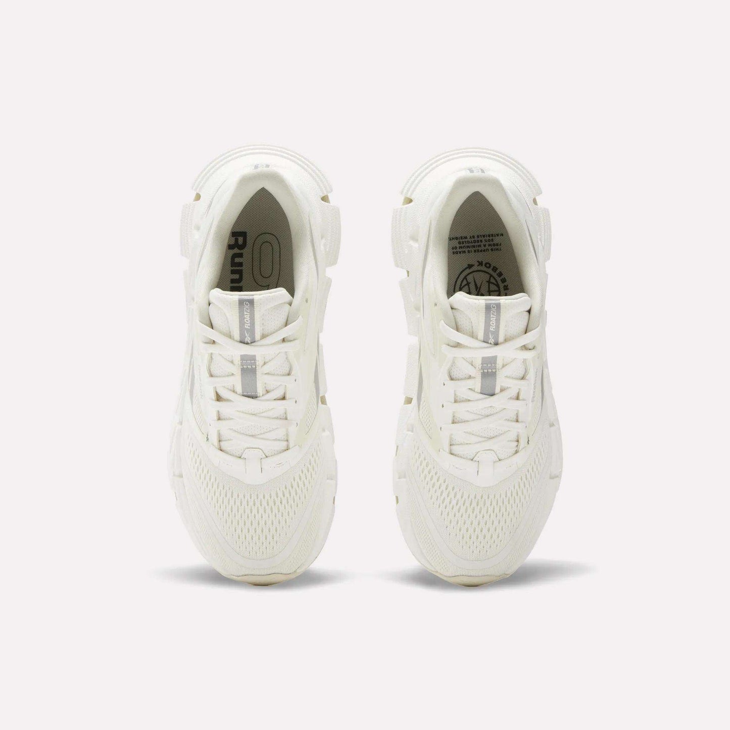 A pair of women's Reebok FloatZig 2 running shoes in white, seen from above, showcase mesh uppers, laces, and subtle Reebok branding on the insoles and tongue, with energy-returning cushioning against a plain light background.