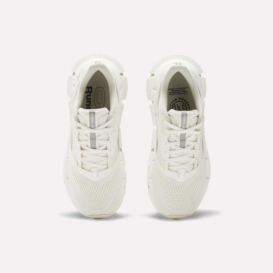 A pair of women's Reebok FloatZig 2 running shoes in white, seen from above, showcase mesh uppers, laces, and subtle Reebok branding on the insoles and tongue, with energy-returning cushioning against a plain light background.