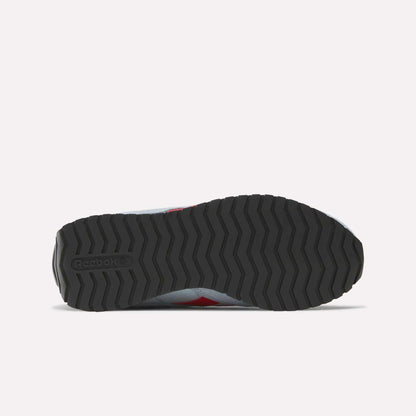 The image shows the bottom view of a Reebok Women's Classic AZ Shoes sneaker, featuring a black zigzag rubber sole with the Reebok logo on the heel. The upper edges are visible, reflecting classic retro running style.