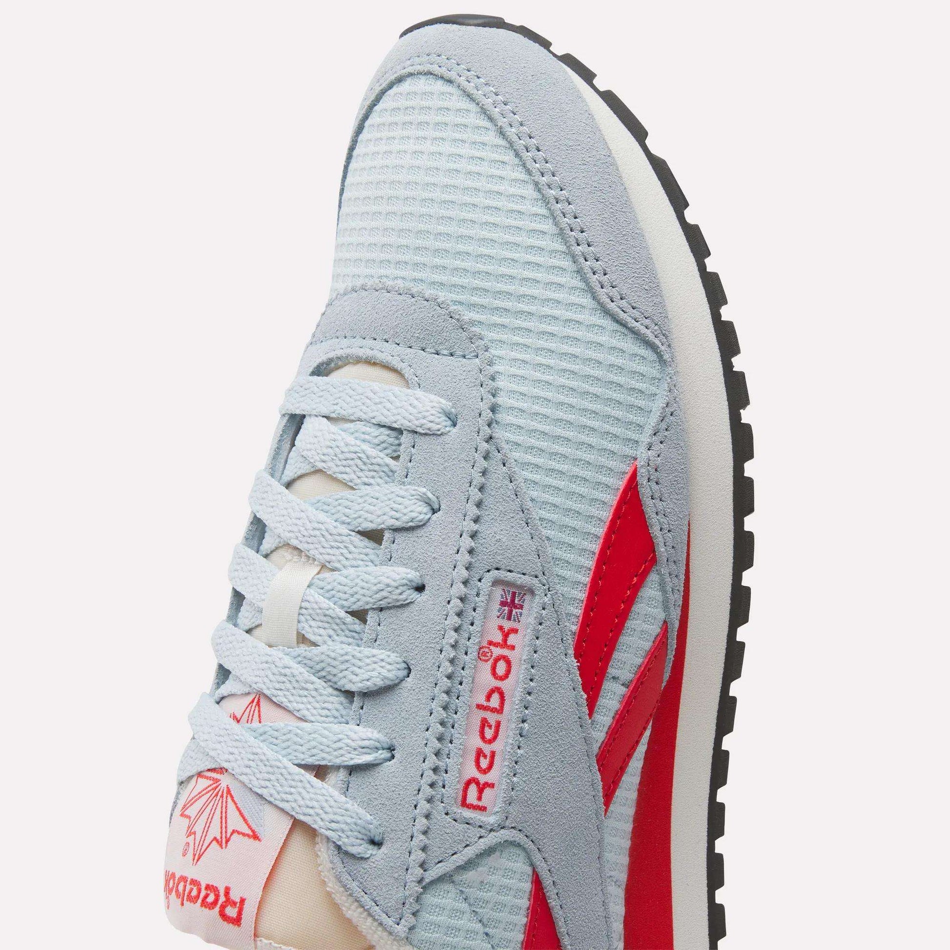 Close-up of a Women's Classic AZ Shoe by Reebok featuring a light blue mesh upper, suede accents, retro-inspired red logo and stripes, white laces, and a black rubber sole.
