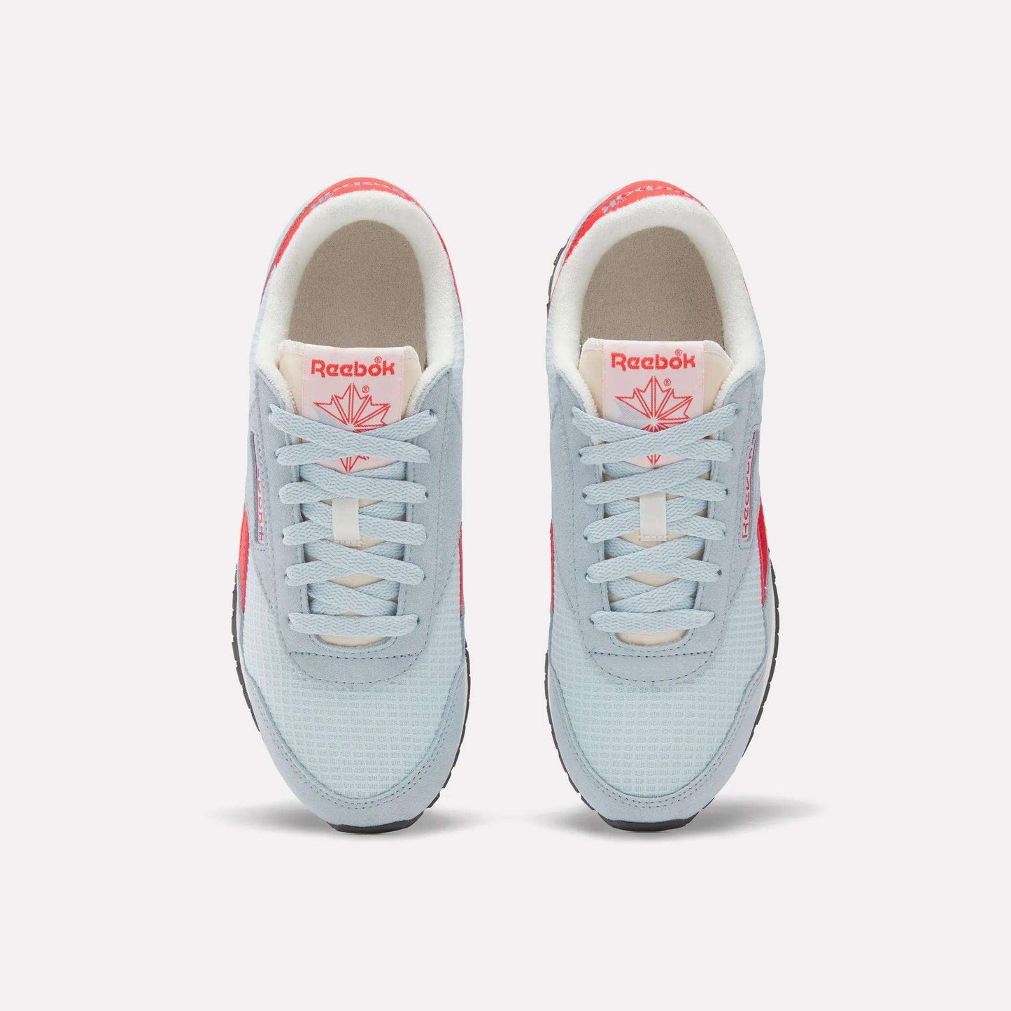 A pair of Women's Classic AZ Shoes by Reebok seen from above, with light blue uppers, white laces, beige interiors, and bright pink Reebok logos—retro running-inspired style with fresh pops of color.