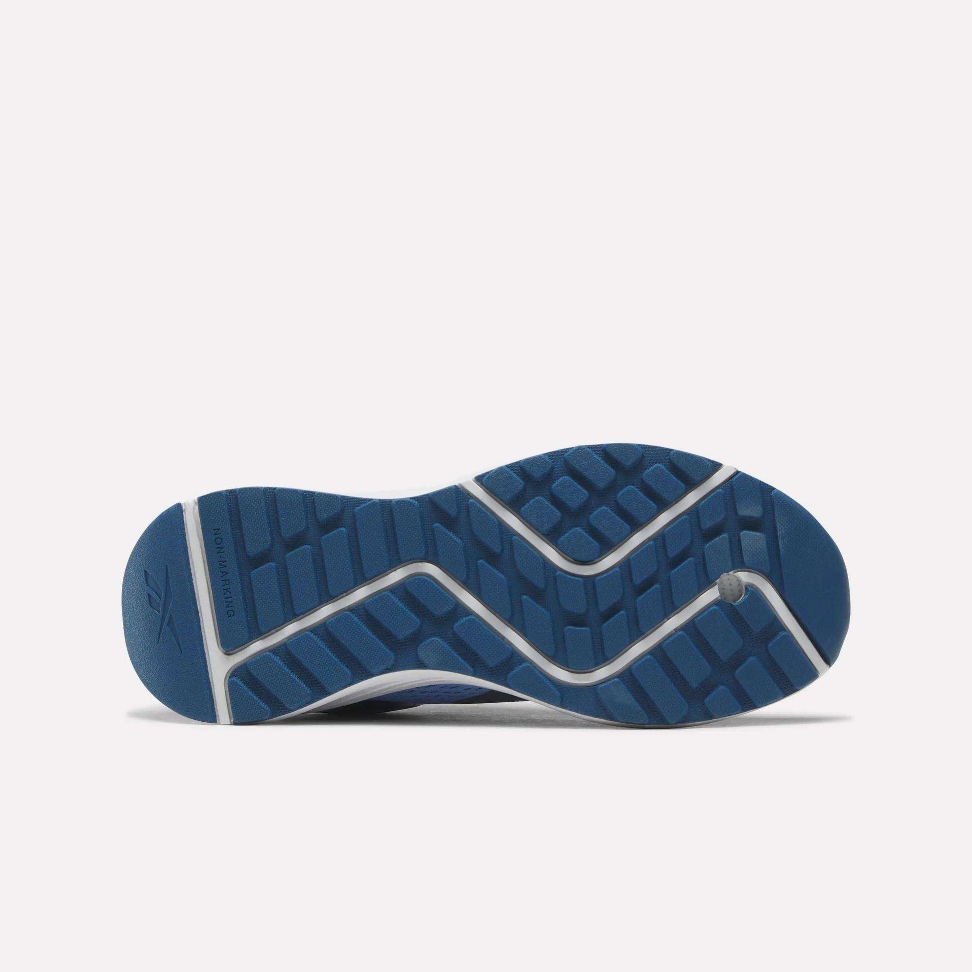 The image displays the blue rubber outsole of the Reebok Energen Running Shoes for little kids, highlighting a zigzag tread pattern and a small logo near the heel against a plain white background.