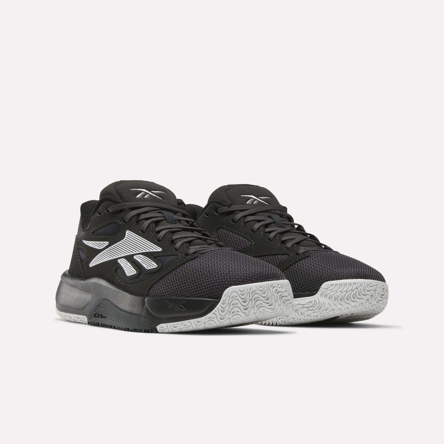 A pair of Reebok Engine LT Shoes with black mesh uppers, white textured soles, and bold white Reebok logos on the sides, shown on a plain light background.