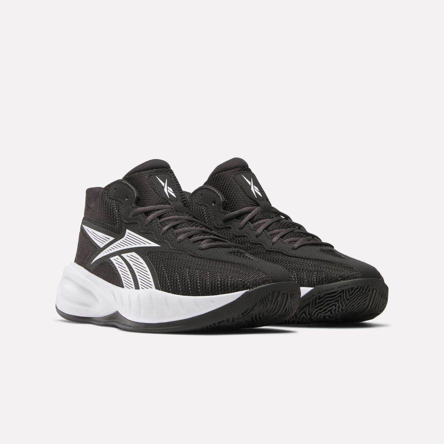Reebok Press Basketball Shoes in black with white accents and soles, featuring a bold white side logo and EVA cushioning for comfort, are displayed against a plain light background.