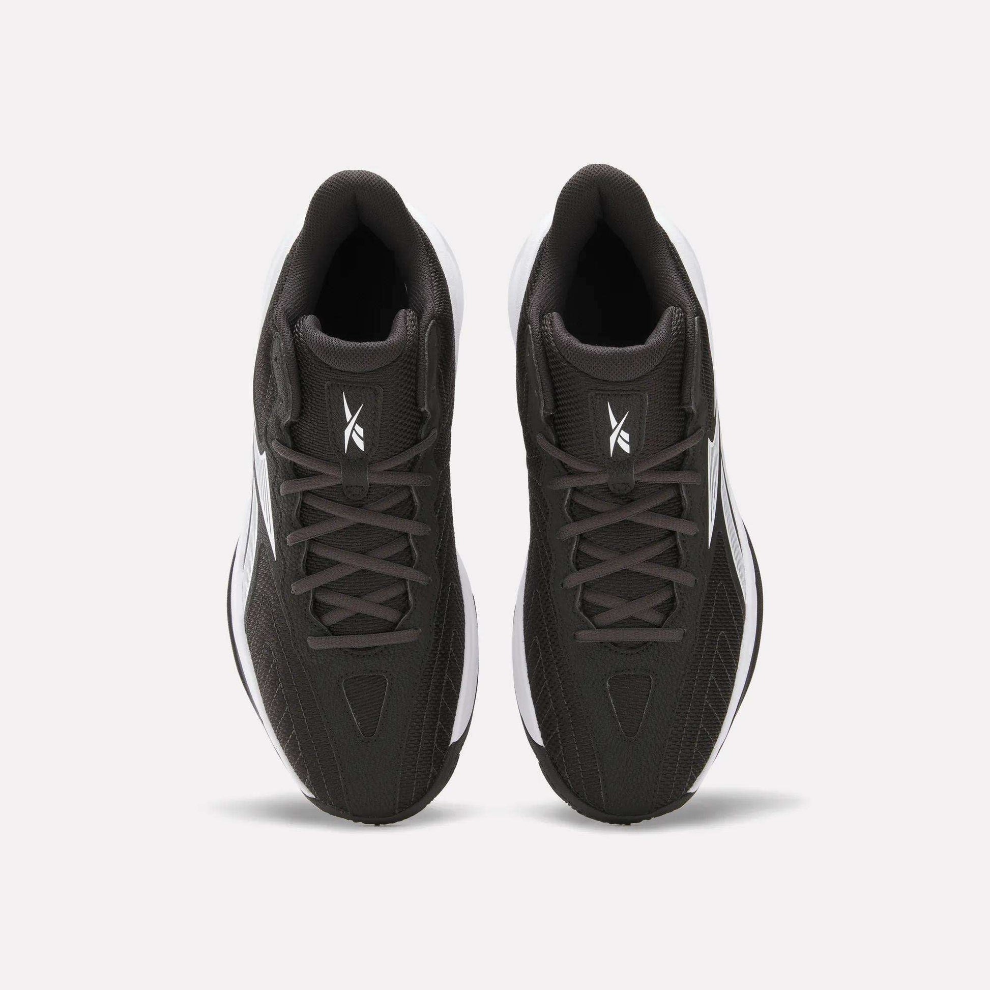 Top view of Reebok Press Basketball Shoes in black with white soles and logo on the tongue, shown side by side on a white background. These shoes offer responsive comfort with EVA cushioning.