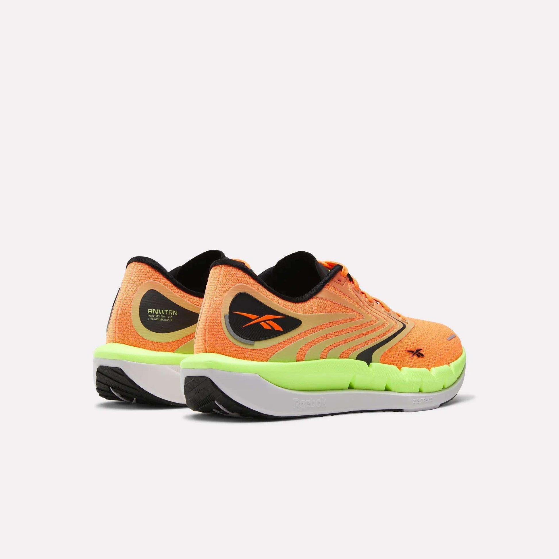 The Reebok Men's FloatZig Tread Running Shoes in orange and neon green with black and yellow accents, featuring a cushioned midsole, are shown from the back and side on a plain white background. Ideal for treadmill workouts.