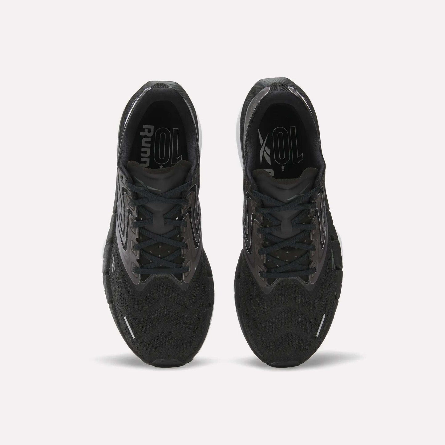 Top view of Reebok Men's FloatZig Tread Running Shoes in black with cushioned midsoles and grey accents, side by side on a white background. Insoles display “Run” and “XOL” in white—ideal for treadmill sessions.