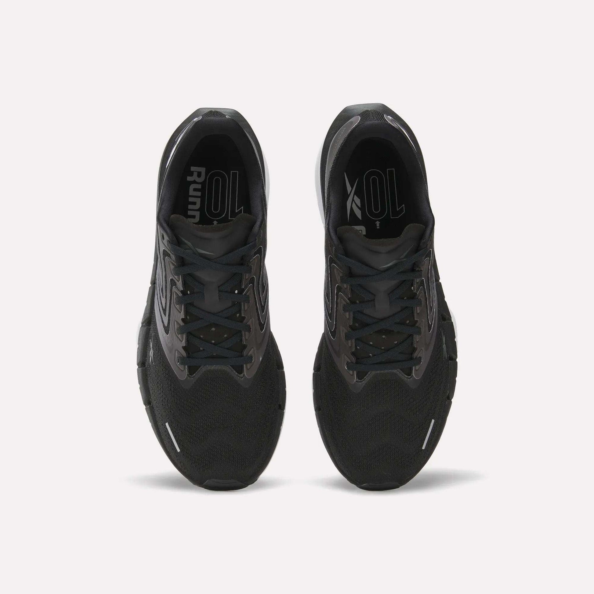 Top view of Reebok Men's FloatZig Tread Running Shoes in black with cushioned midsoles and grey accents, side by side on a white background. Insoles display “Run” and “XOL” in white—ideal for treadmill sessions.