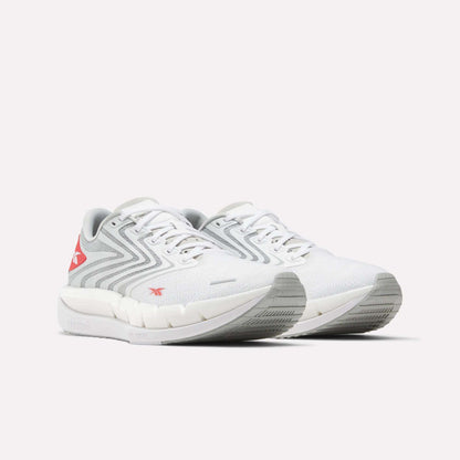 The Reebok Men's FloatZig Tread Running Shoes in white with light gray and red accents feature a zigzag side design, cushioned midsole, and textured sole—perfect for treadmill workouts—shown on a plain white background.