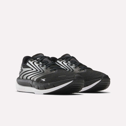 A pair of Reebok Women's FloatZig Tread Running Shoes in black and white, featuring breathable mesh uppers, zigzag side details, white soles, and Reebok branding—ideal for treadmill workouts—shown on a plain white background.