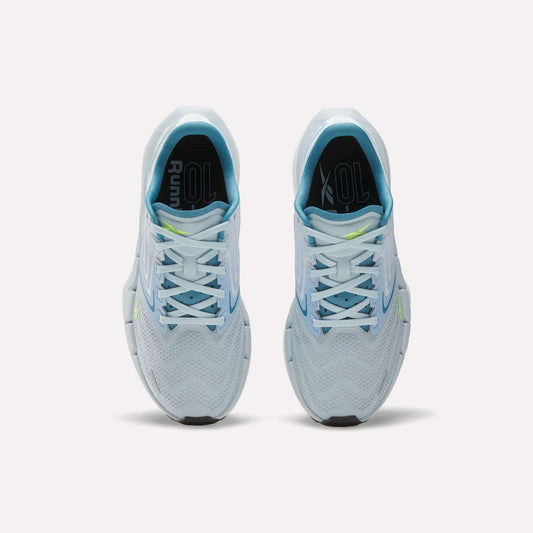 Top view of Reebok Women's FloatZig Tread Running Shoes in light blue with white laces, breathable mesh, and a yellow accent on the right tongue, side by side on a plain white background—ideal for treadmill workouts.