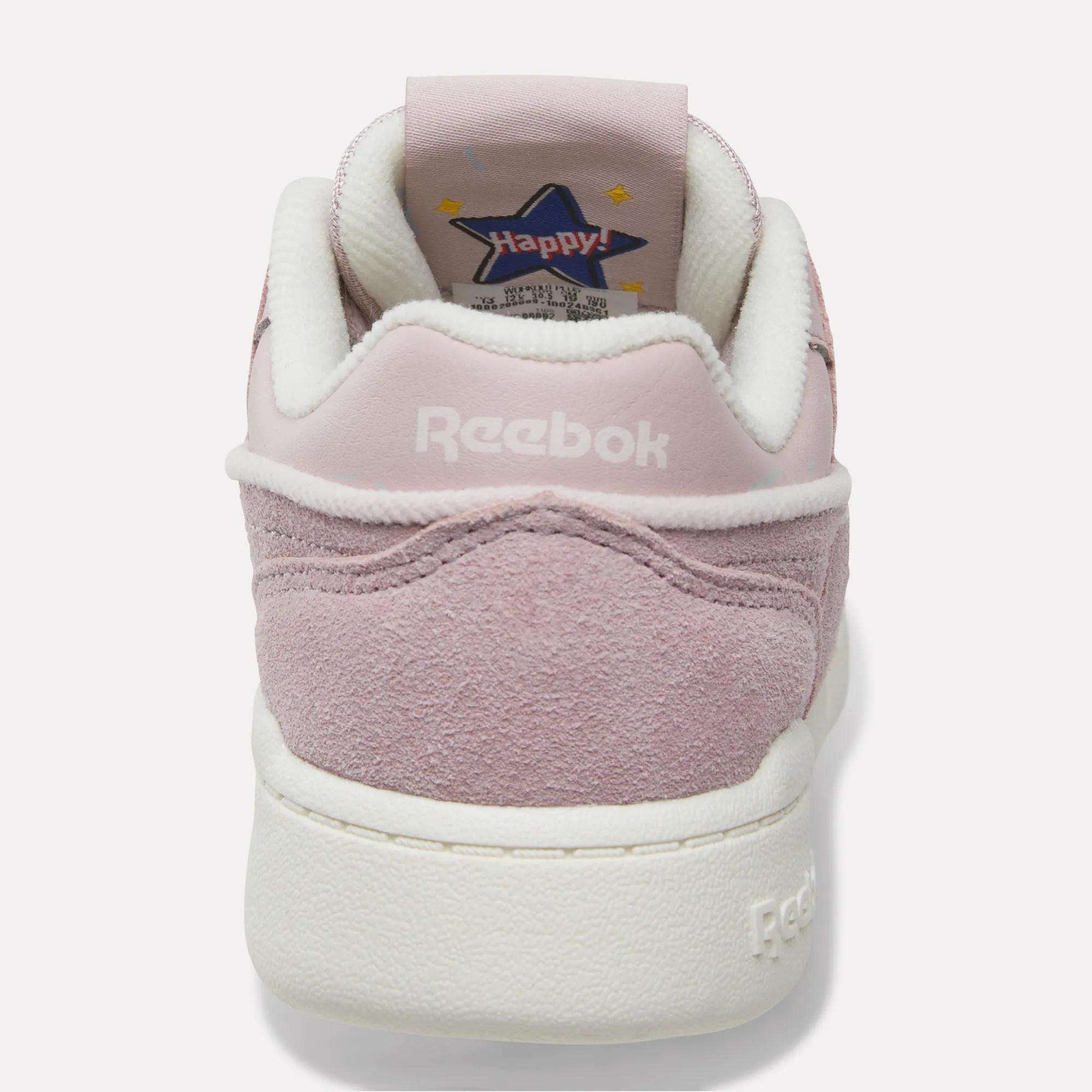 A pink suede Reebok Workout Plus Shoe for little kids, shown from the back with “Reebok” stitched in white on the heel and a star-shaped “Happy!” graphic on the inner tongue—sporty and perfect for any fun outing.