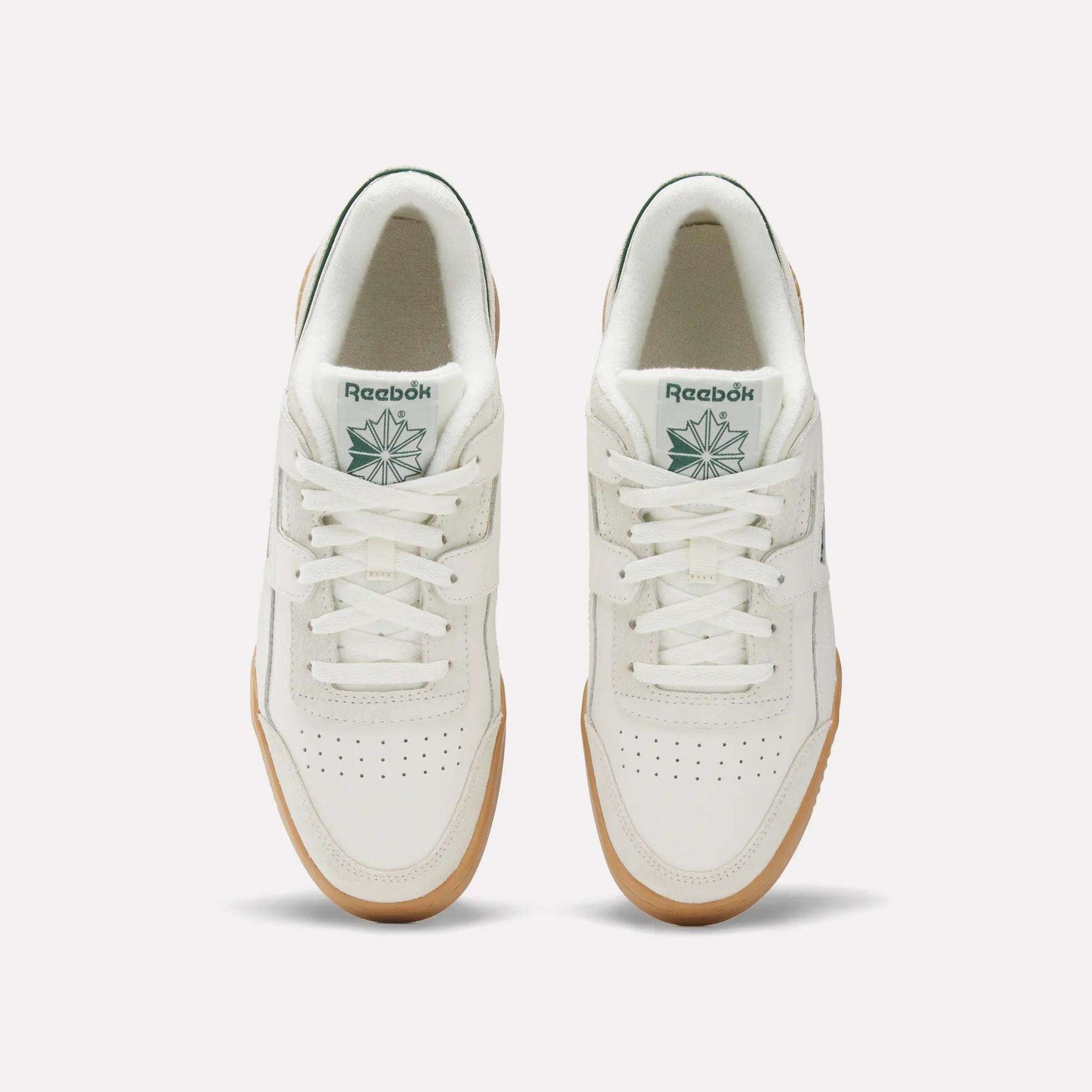A top view of Reebok Workout Plus Shoes with white uppers, gum soles, white laces, perforated toe boxes, and green Reebok logos on the tongues—capturing classic '80s fitness style.