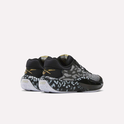 Reebok Engine A 26 Basketball Shoes in black and white feature a spotted pattern, gold accents, white soles with ERS+ cushioning, and are displayed from the rear and side on a plain light background.
