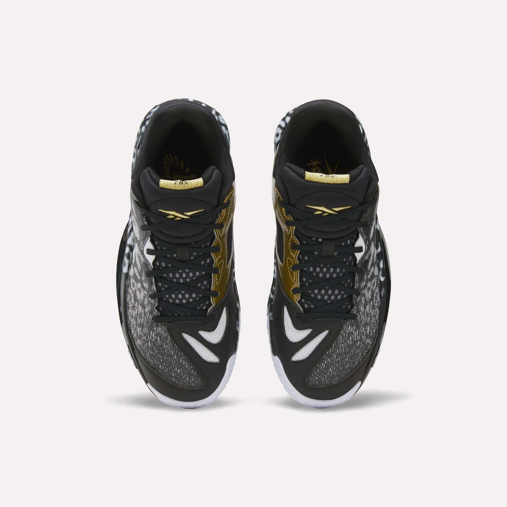 Top view of a pair of Reebok Engine A 26 Basketball Shoes in black with white and gold accents, featuring patterned toe and side panels, white outsoles, and ERS+ System cushioning for game-changing comfort.
